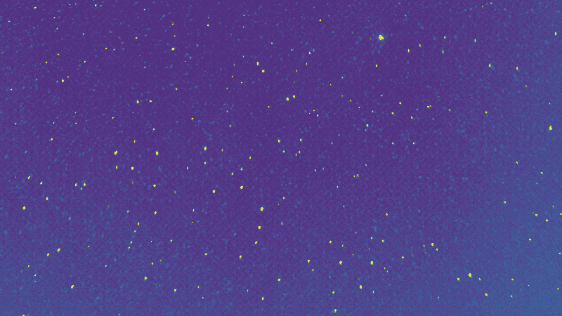 A bright flash in front of a field of stars leaves a faint snakelike trail drifting in its wake; another shooting star is visible in the background