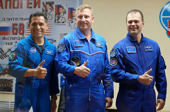 U.S. astronaut Frank Rubio and cosmonauts Sergey Prokopyev and Dmitri Petelin stand in a row, giving thumbs ups