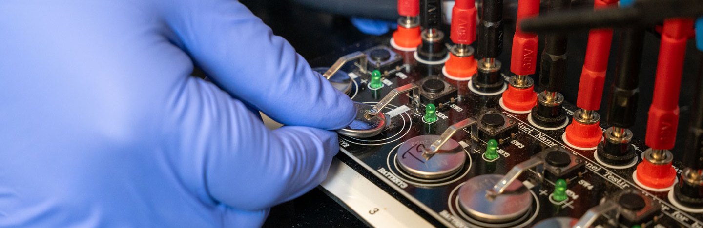 cell batteries with hand in purple glove