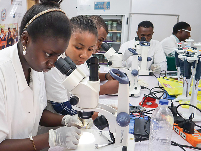 A photograph of researchers looking through microscopes in a biological lab at the Drosophila Research Training Centre in Nigeria