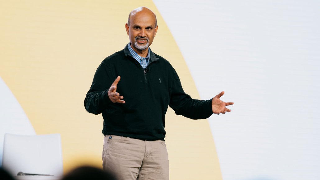 Mohamad Ali, Senior Vice President for IBM Consulting, gestures broadly while standing on a stage.