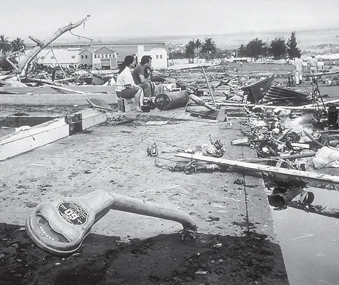 Two people in Hawaii sit amid wreckage caused by a 1960 tsunami.