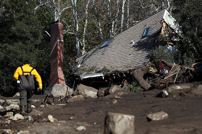 A firefighter walks towards a destroyed house.