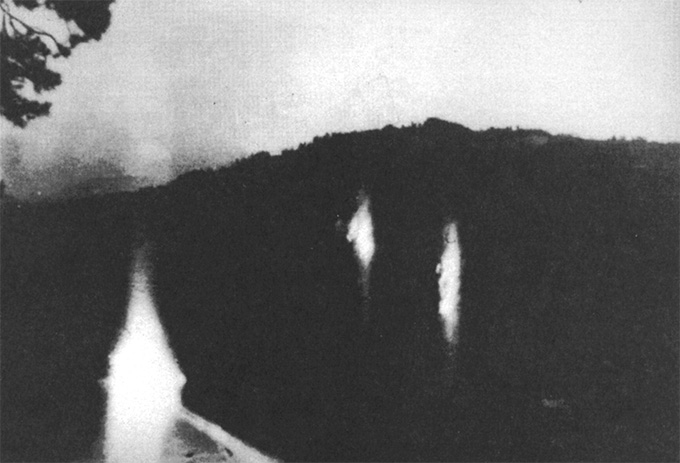 Three lights floating in a dark setting, in a black and white photo.