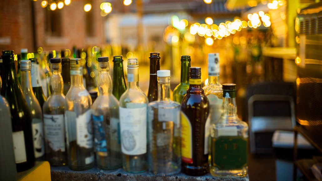 Glass bottles of alcohol sit on a shelf.