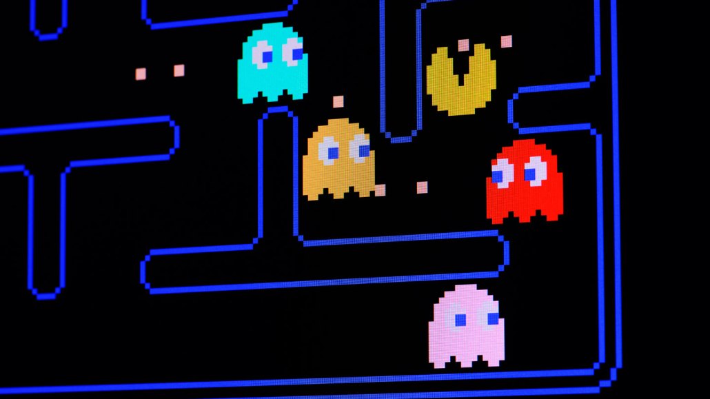 Pac-Man on a black video game screen surrounded by colorful ghosts.