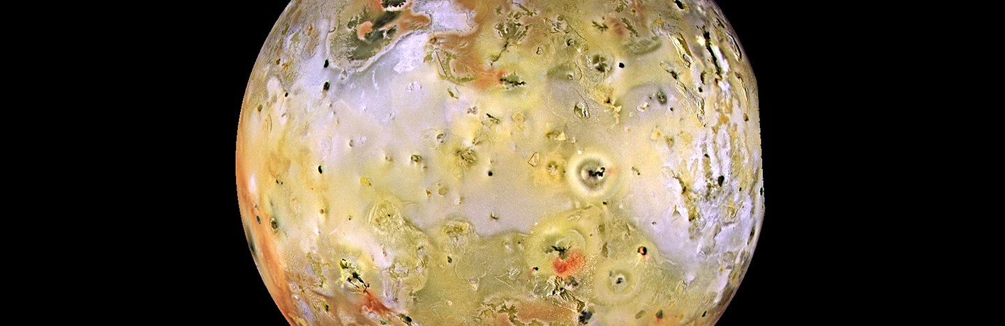 This image shows Jupiter's moon Io, taken from the Galileo spacecraft. It looks like a yellowish pockmarked world on a black background.