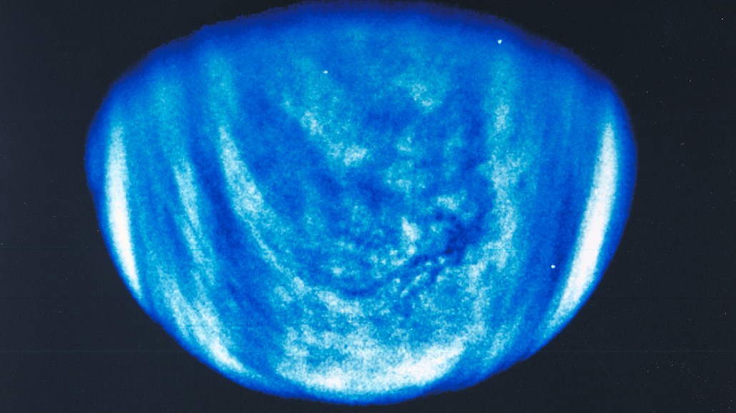 A blue hemisphere fills the bottom of the image. White wispy clouds swirl on its surface.