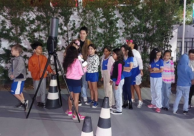 Children and parents gathered around a telescope.