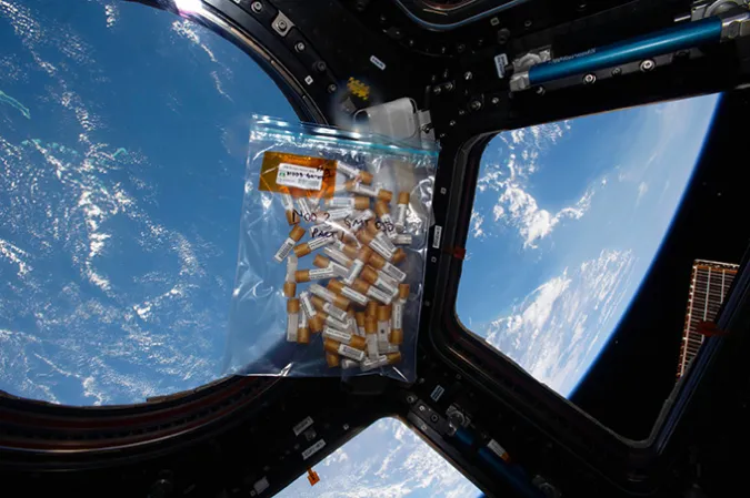 a bag of sampling devices on the space station, Earth in background