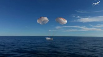 Giant parachutes float above the capsule that carried astronauts back to Earth from the International Space Station.