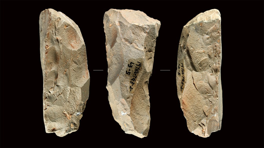 Three chisled stone tools known as Quina scrapers, made by early human ancestors, are shown on a black background