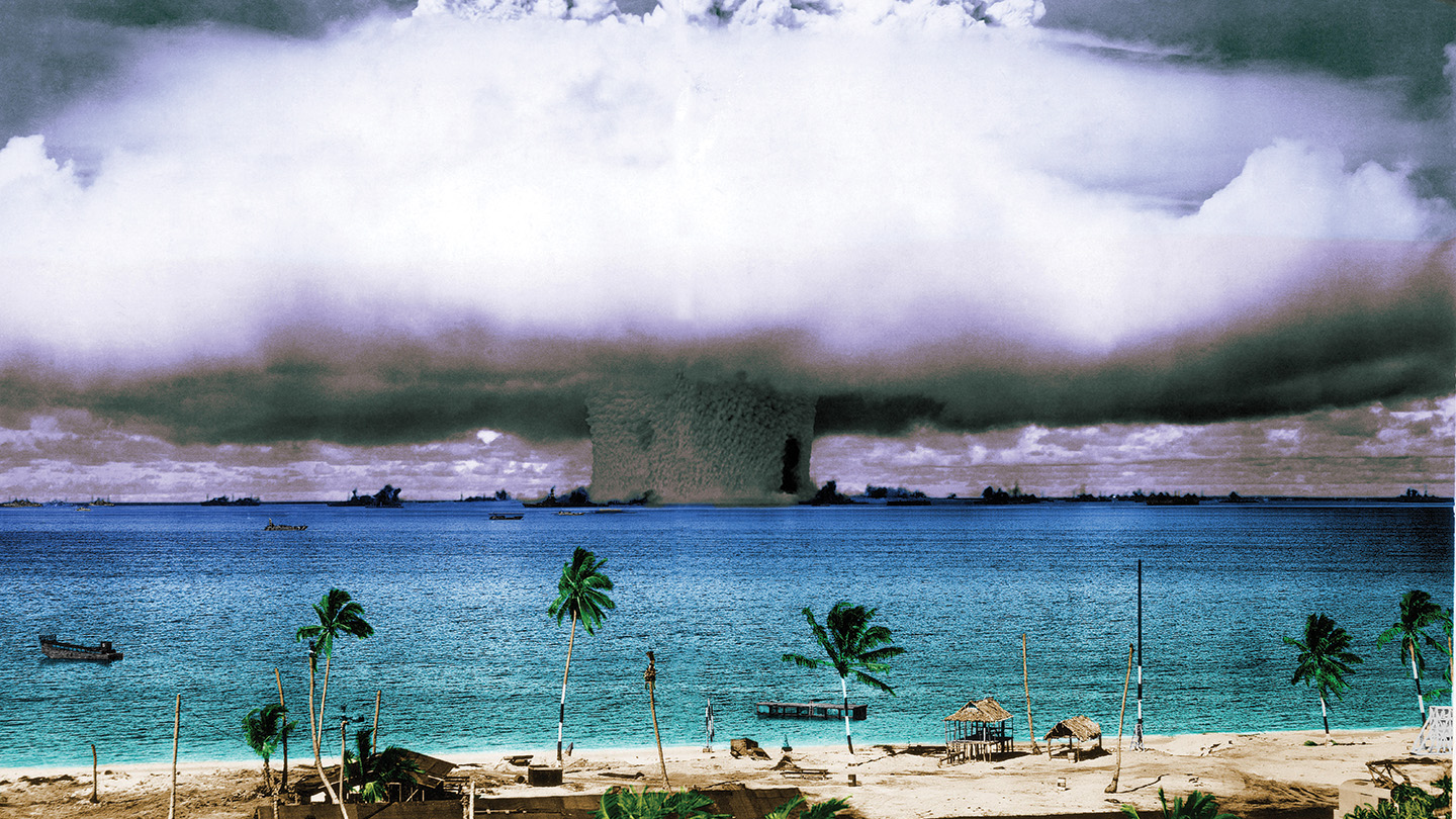The smoke plume from a nuclear test in Bikini Atoll along a beach front.