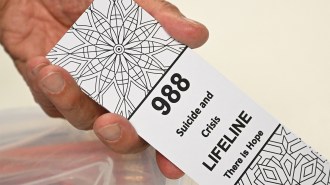 A photo of a hand holding a card that reads "988 Suicide and Crisis Lifeline There is Hope"