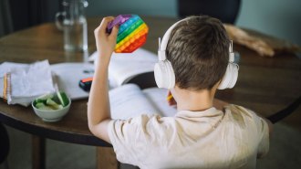 A child wearing headphones plays with colored blocks