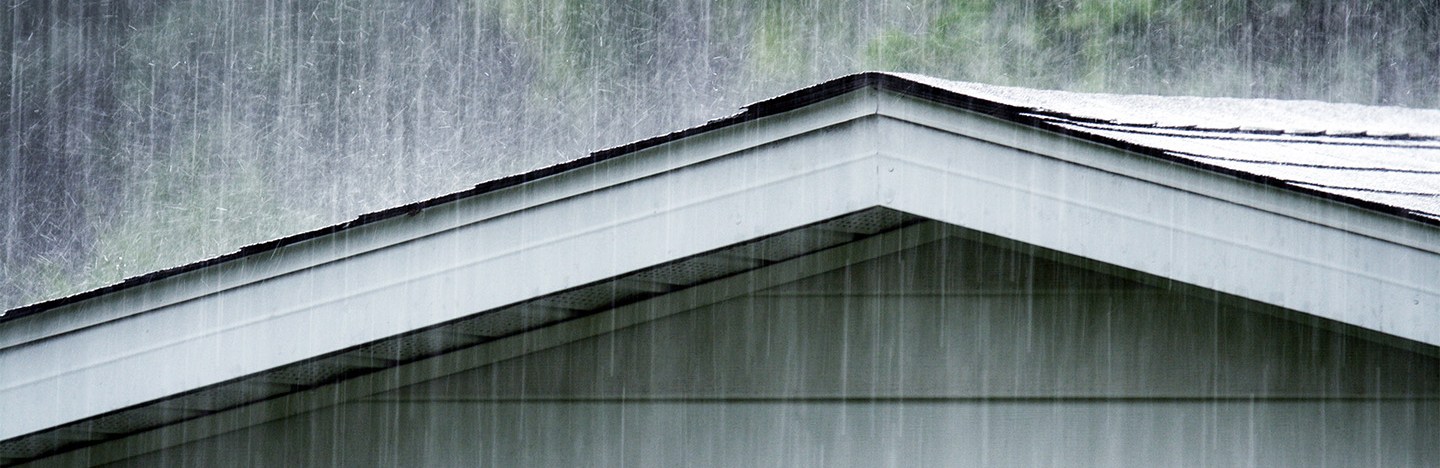 A photo shows raindrops falling on a shingle roof.
