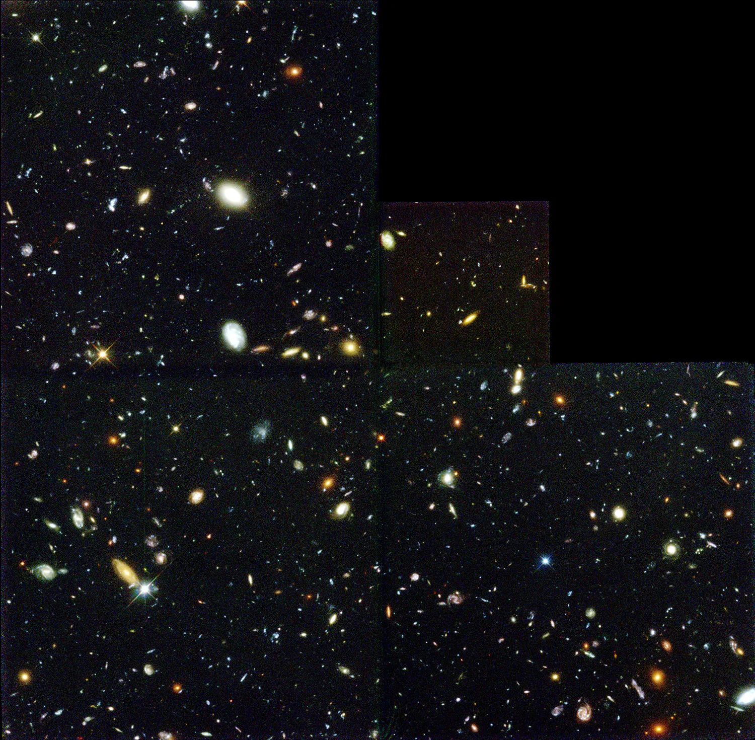Hundreds of galaxies, some reddish, some blueish, some white, fill the black background of space.