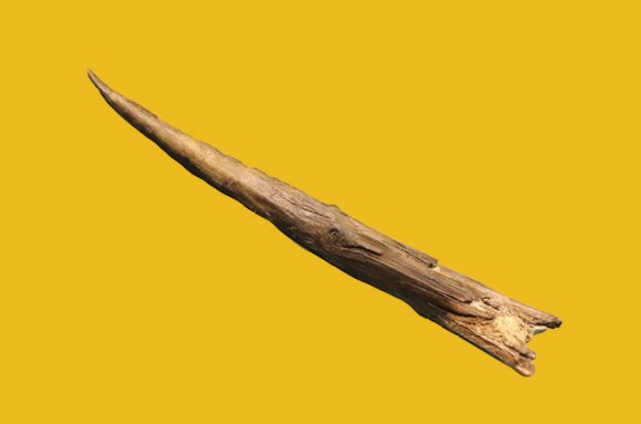 A wooden spear against a yellow background.