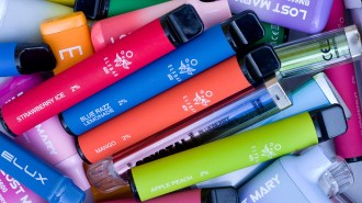 A pile of colorful disposable vape pens with various flavors labeled, such as strawberry ice, blue razz lemonade, mango, apple peach and blueberry raspberry.