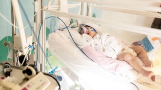 A baby lying in a hospital bed, eyes close, receiving treatment for a lung infection
