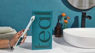 A hand holds the Teal Wand, a long, thin device for at home cervical cancer screening.