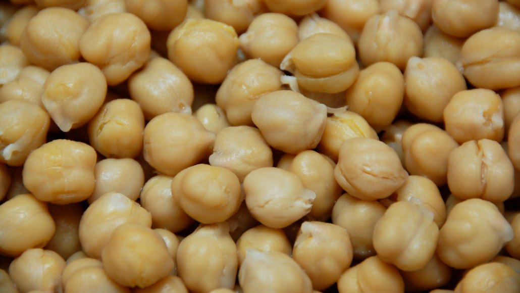 A close up of chickpeas, also known as garbanzo beans, which are round and tan.