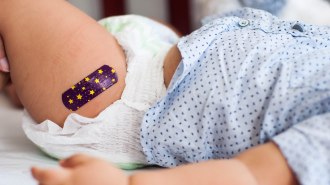 A closeup of a baby's thigh with a purple bandaid with yellow stars, suggesting a vaccination site.