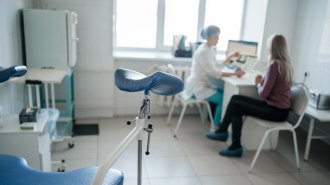 A gynecologist and a patient sit at a desk reviewing medical results.