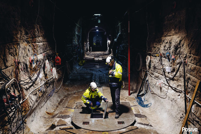 Two people work inside a long, dimly lit tunnel.