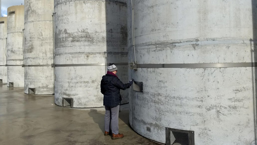 A person stands next to a row of large concrete cylinders used for storing nuclear waste.