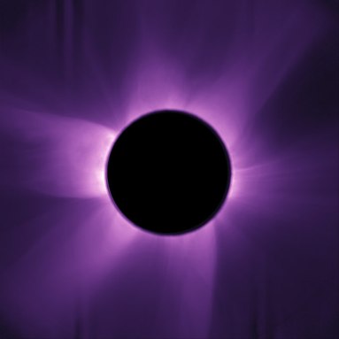 A black circle perfectly blocks the sun in an artificial solar eclipse. The sun's corona and wispy rays radiate from it in purple.