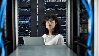 Female technician stands in a server room.