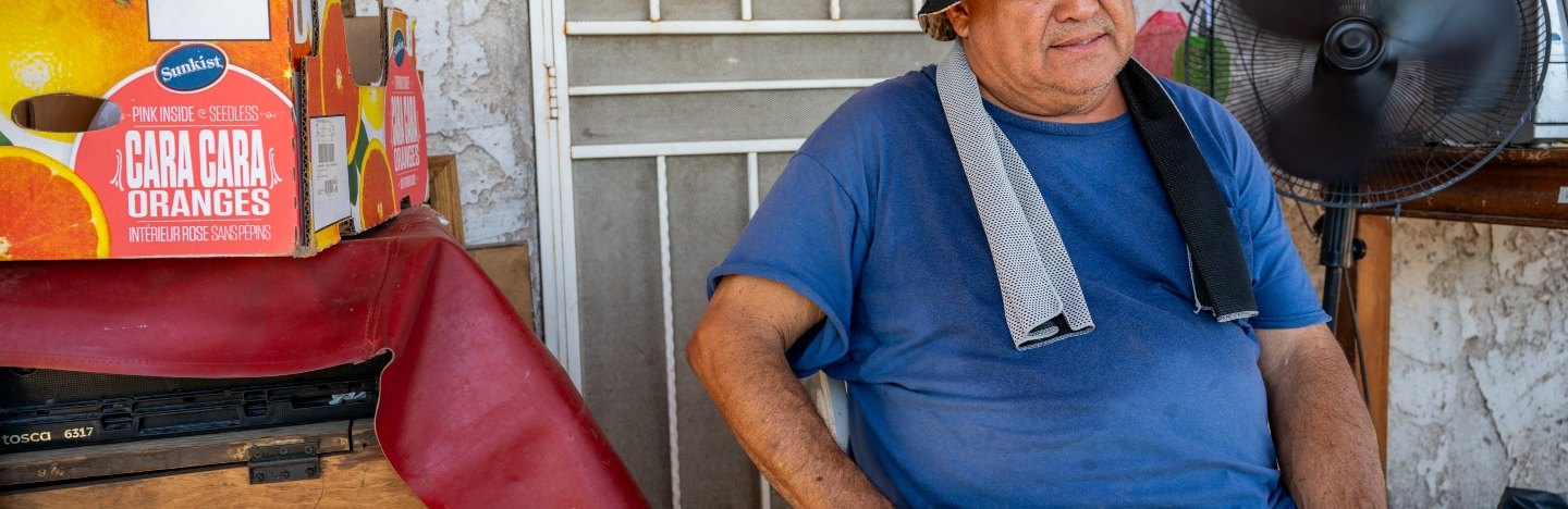 a sweating man sits in a chair front of a house