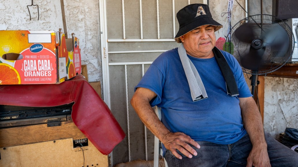 a sweating man sits in a chair front of a house