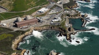 Aerial shot of the Diablo Canyon power plant, California’s last operational nuclear energy source. We see a craggy coast line surrounding the plant and areas of frothy white ocean near the plant's wash.