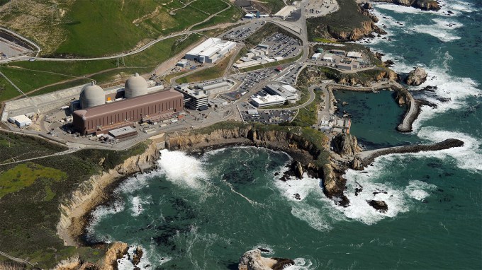 Aerial shot of the Diablo Canyon power plant, California’s last operational nuclear energy source. We see a craggy coast line surrounding the plant and areas of frothy white ocean near the plant's wash.