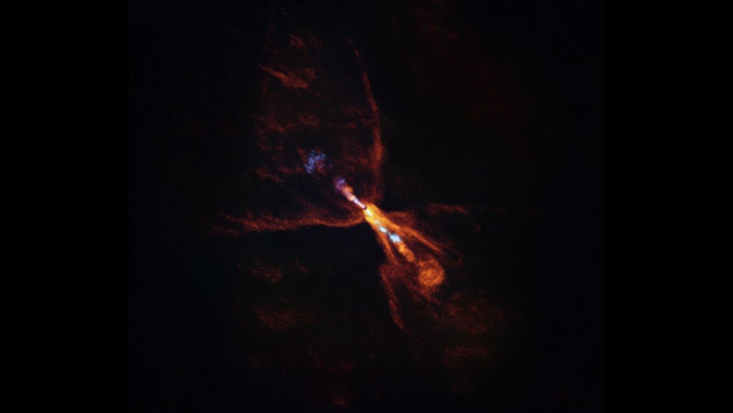 Gas blowing away from a baby star are shaped like a butterfly. They're outlined in orange, representing carbon monoxide gas, with some splotches of orange inside. Some blue blotches run in a horizontal line across the wings, showing a jet with silicon monoxide gas.