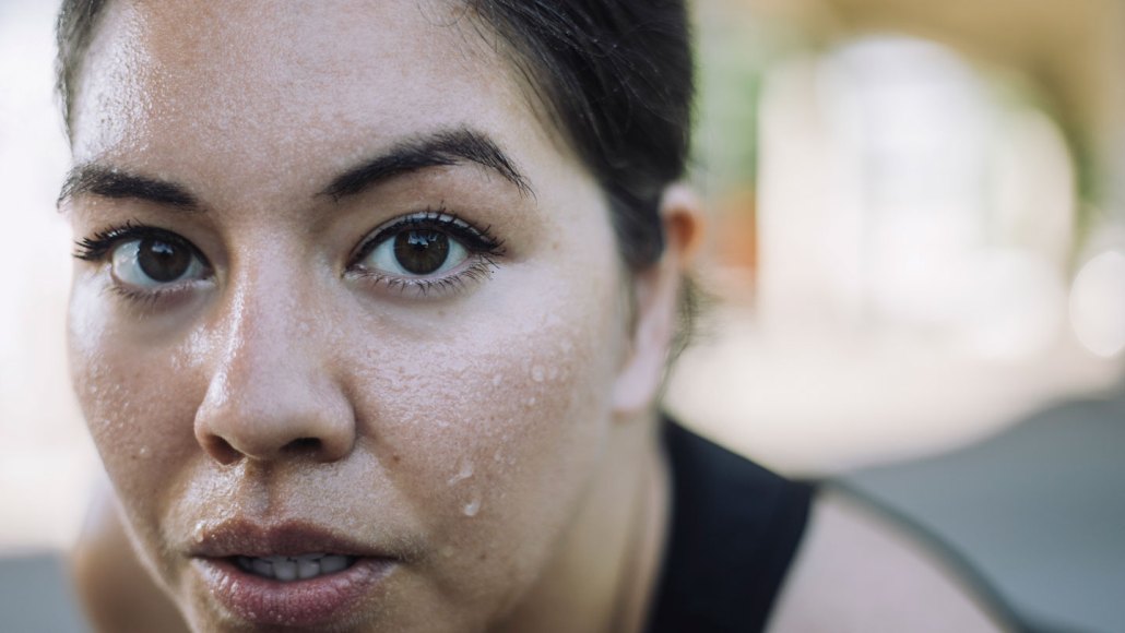 A closeup of a woman's face that's covered with sweat.