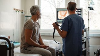 A doctor and patient in an exam room look at a screen with an image of the patient's colon