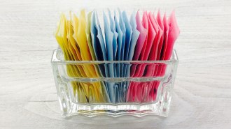 Packets of artificial sweeteners in a clear container.