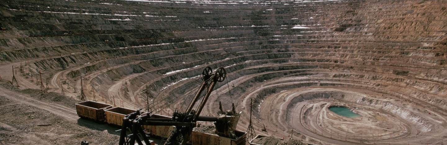 An excavator works inside of a large mining pit.