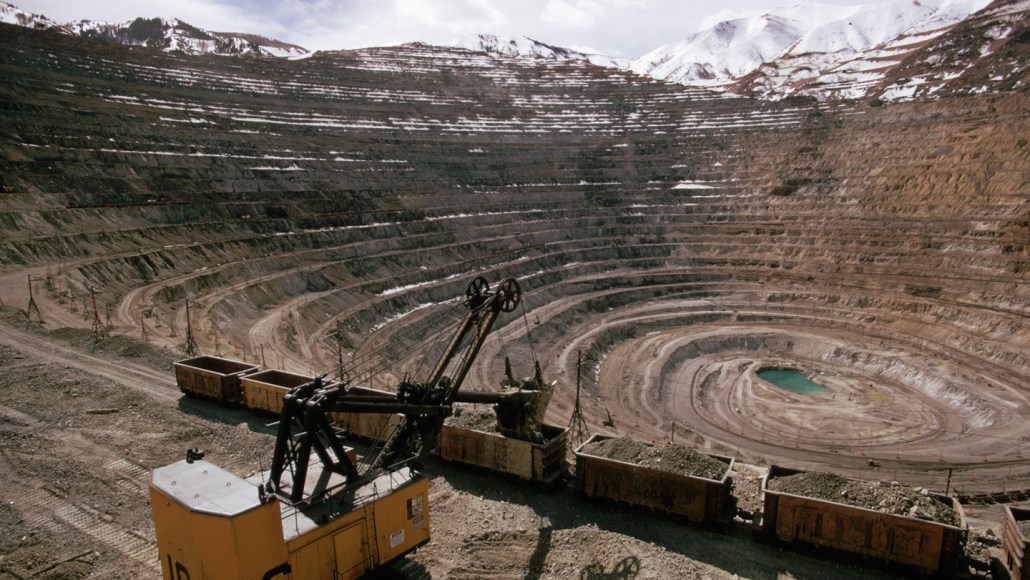 An excavator works inside of a large mining pit.