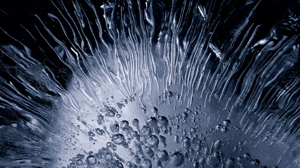 an image of ice shows bubbles and striations radiating from lower center. Regular ice like this can only generate a weak current, but when slabs of saltwater ice are bent, they can produce a stronger electrical current, known as the flexoelectric effect.