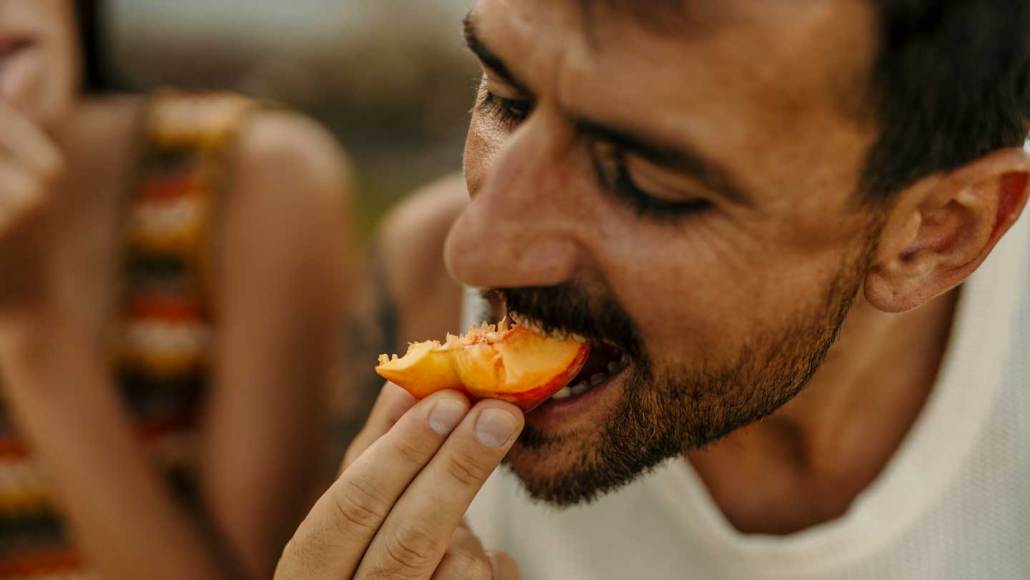 A man biting into a peace slice
