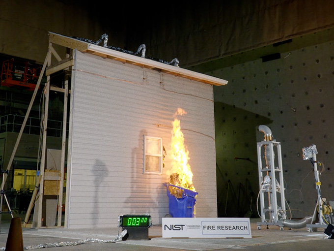 Trash bin next to a model house on fire