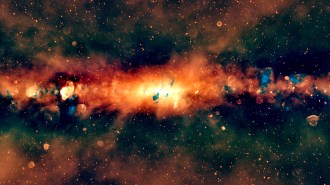 Image of the galactic center glowing red in artificially colored radio wavelengths of light. Red and blue splotches indicate other objects and phenomena emitting radio light.