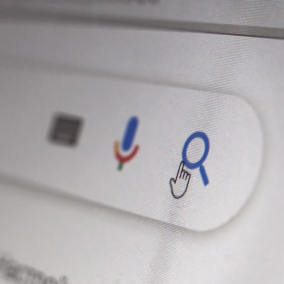 A closeup view of a computer screen shows a little hand icon about to hit the search button.