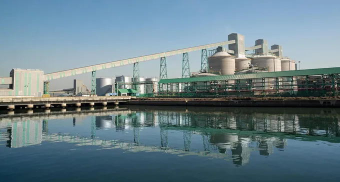 An aluminum smelting plant in Mozambique is shown reflected off still water in the foreground