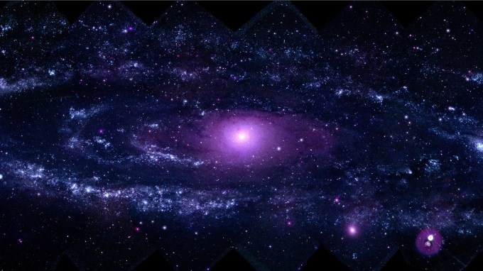 A large spiral galaxy glows in purple light.