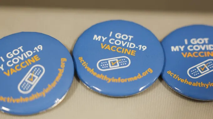 Image of blue pins with I got my COVID-19 vaccine written in white and yellow with a bandaid